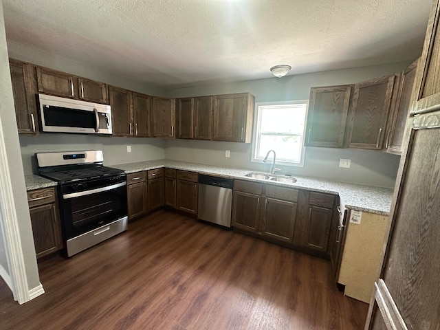 kitchen featuring stainless steel appliances, sink, dark hardwood / wood-style flooring, and a textured ceiling