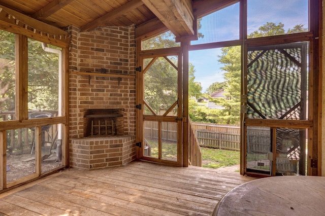 unfurnished sunroom featuring lofted ceiling with beams, wood ceiling, and a wealth of natural light