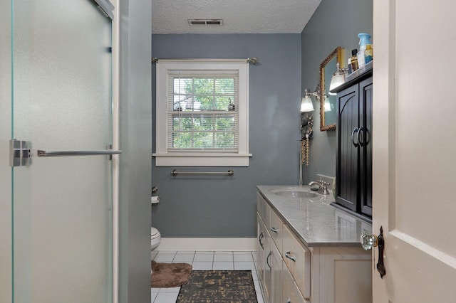 bathroom with tile patterned floors, vanity, a textured ceiling, and toilet