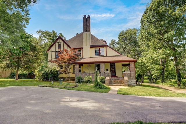 tudor-style house featuring a front yard and a porch