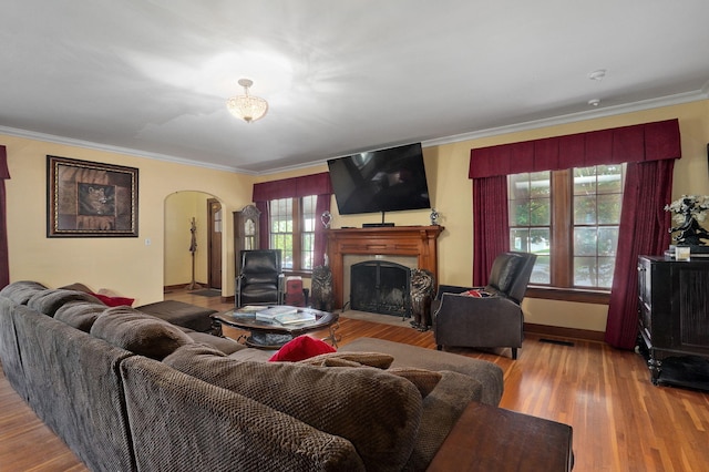 living room with wood-type flooring, ornamental molding, and a wealth of natural light