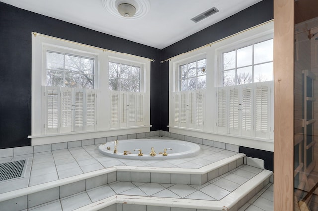 bathroom with tile patterned flooring and tiled tub