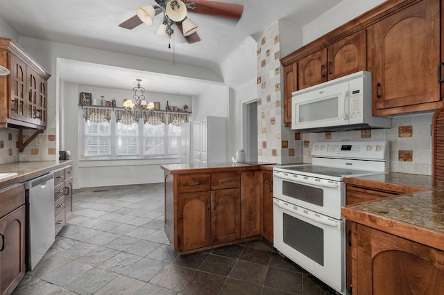 kitchen featuring ceiling fan with notable chandelier, white appliances, backsplash, and hanging light fixtures