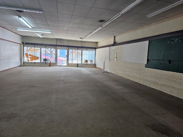 empty room with a paneled ceiling and concrete floors