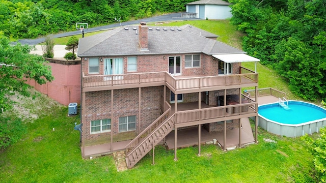 back of property with brick siding, a yard, a chimney, and a wooden deck