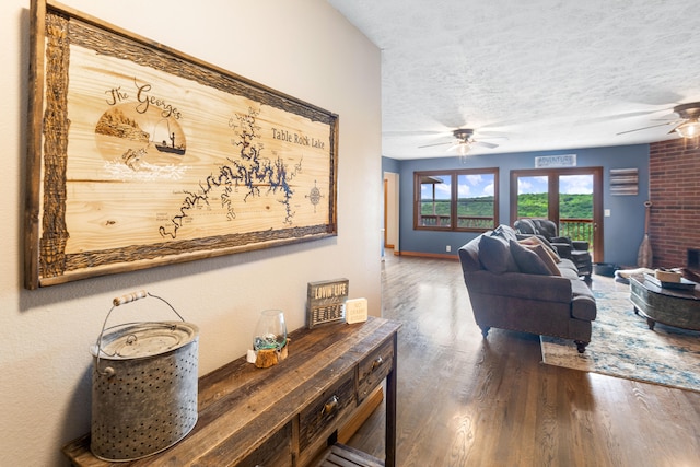 living room with ceiling fan, dark wood-type flooring, and a textured ceiling