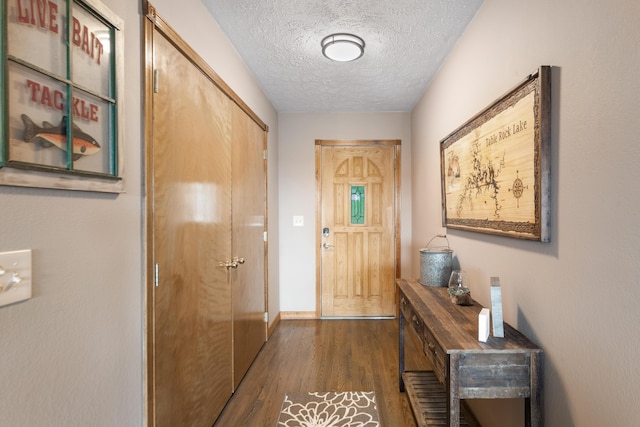 doorway to outside with baseboards, a textured ceiling, and dark wood-style floors