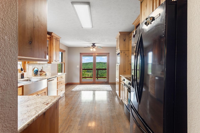 kitchen featuring wood finished floors, a ceiling fan, baseboards, tasteful backsplash, and appliances with stainless steel finishes