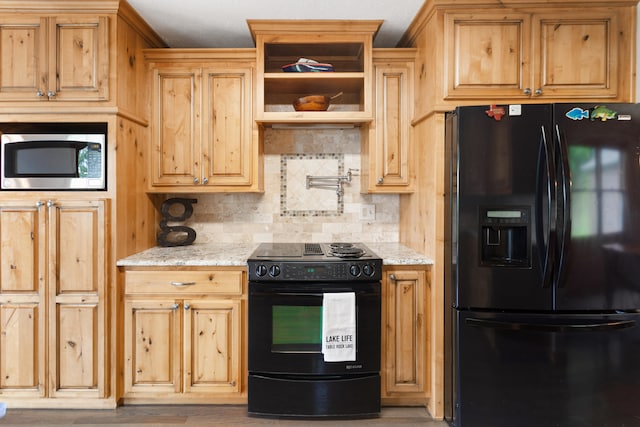 kitchen with light hardwood / wood-style flooring, light stone countertops, backsplash, and black appliances