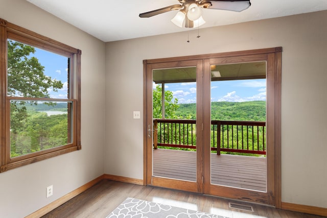 doorway to outside featuring visible vents, light wood-style flooring, baseboards, and ceiling fan