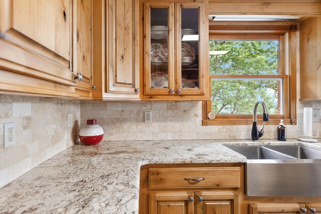 kitchen featuring tasteful backsplash, light stone counters, and sink