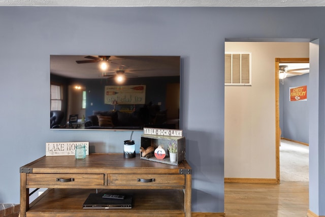 interior details with wood finished floors, baseboards, a ceiling fan, and visible vents