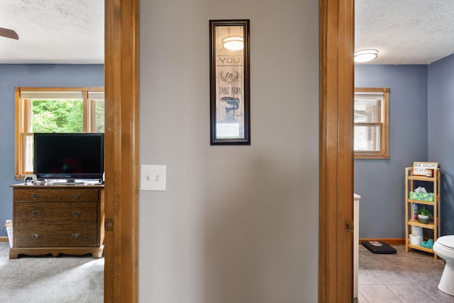 hall with baseboards and a textured ceiling