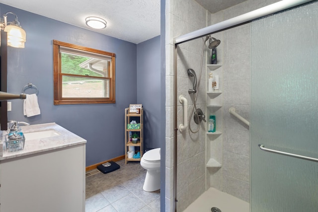 bathroom featuring a shower stall, tile patterned flooring, toilet, vanity, and baseboards
