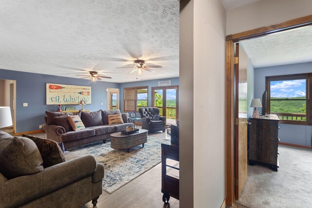 living area featuring baseboards, a ceiling fan, wood finished floors, and a textured ceiling