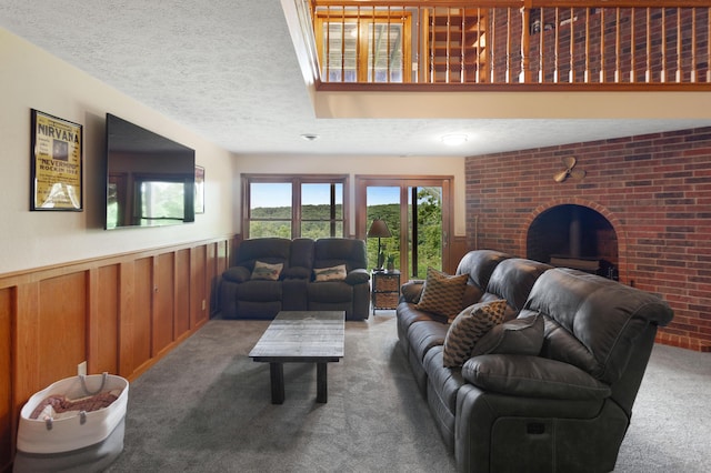 carpeted living area featuring a wainscoted wall, wooden walls, a fireplace, and a textured ceiling