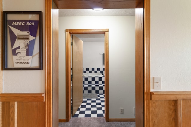 hall with a textured ceiling and carpet flooring