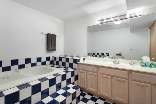 bathroom with vanity, tiled bath, and a textured ceiling