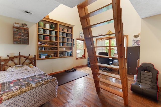 bedroom with baseboards, wood finished floors, and visible vents