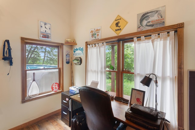 home office featuring baseboards, wood finished floors, and a healthy amount of sunlight