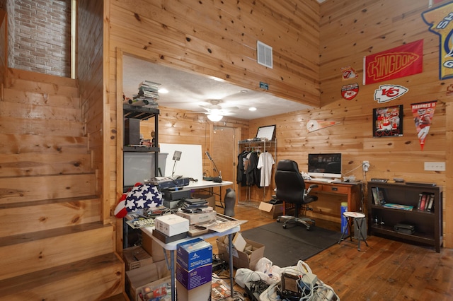 office area featuring wood finished floors, visible vents, wood walls, and a ceiling fan