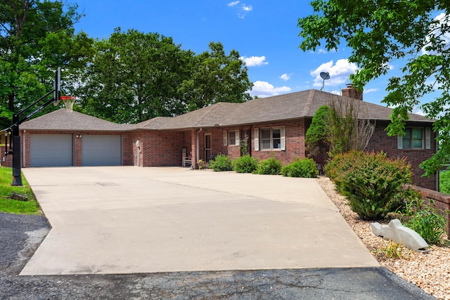 ranch-style house with a chimney, brick siding, driveway, and a garage