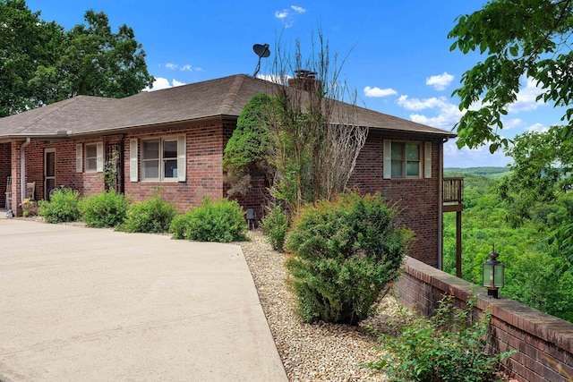 single story home with brick siding, a shingled roof, and a chimney