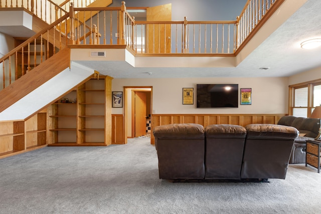 carpeted living room with a textured ceiling and wood walls