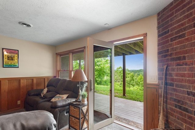 doorway featuring wainscoting, wood walls, a textured ceiling, and visible vents