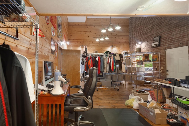 office area with wood walls, brick wall, wood finished floors, and a high ceiling