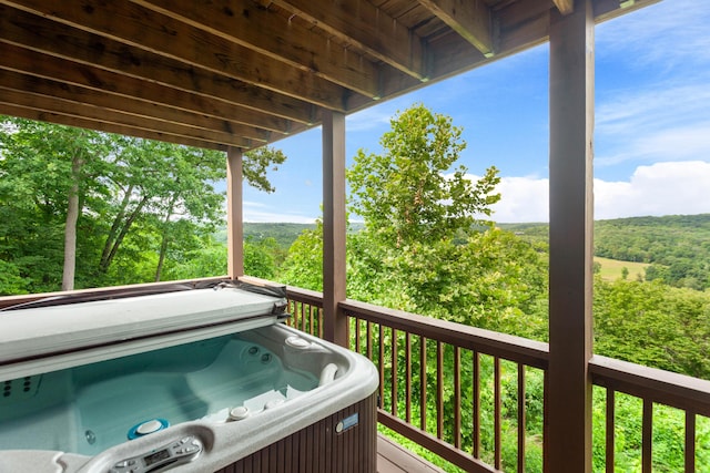 deck with a hot tub and a wooded view