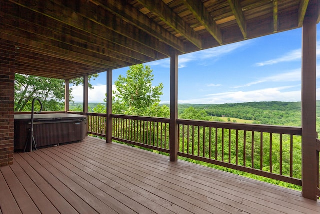wooden terrace featuring a hot tub and a wooded view