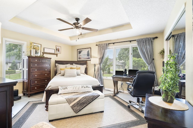 tiled bedroom with ceiling fan, a raised ceiling, and a textured ceiling