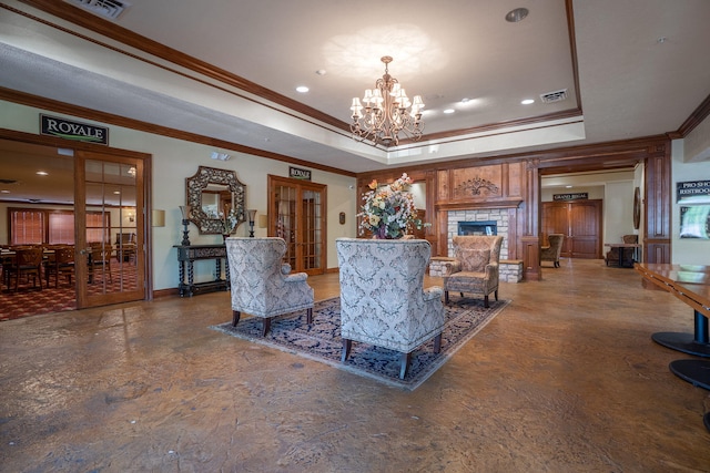 living room with a raised ceiling, french doors, a chandelier, and ornamental molding