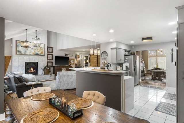 dining space featuring light tile patterned floors, sink, and a tiled fireplace