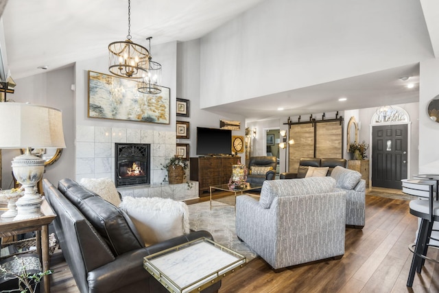 living room featuring a chandelier, dark hardwood / wood-style flooring, high vaulted ceiling, and a tiled fireplace