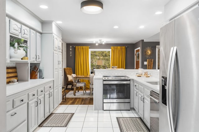 kitchen featuring kitchen peninsula, appliances with stainless steel finishes, sink, light tile patterned floors, and white cabinetry