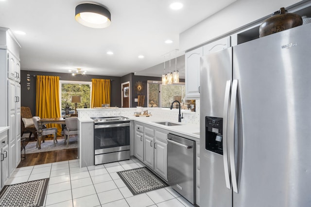 kitchen featuring pendant lighting, sink, decorative backsplash, kitchen peninsula, and stainless steel appliances