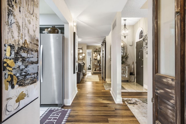 hallway with hardwood / wood-style flooring, a notable chandelier, and a textured ceiling