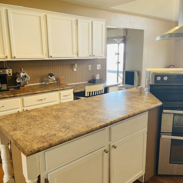 kitchen featuring stainless steel range, range hood, and white cabinets