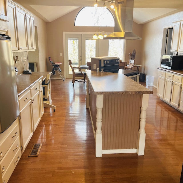 kitchen with stove, hanging light fixtures, island range hood, a kitchen island, and french doors