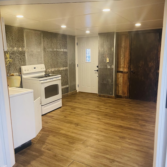 kitchen featuring washer / clothes dryer, electric range, wood-type flooring, and white cabinets