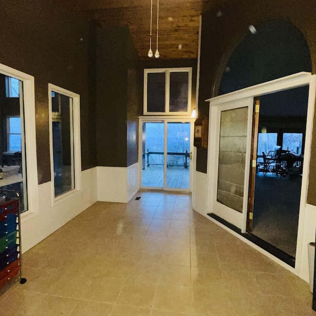 hallway with french doors, a towering ceiling, tile patterned flooring, and wooden ceiling