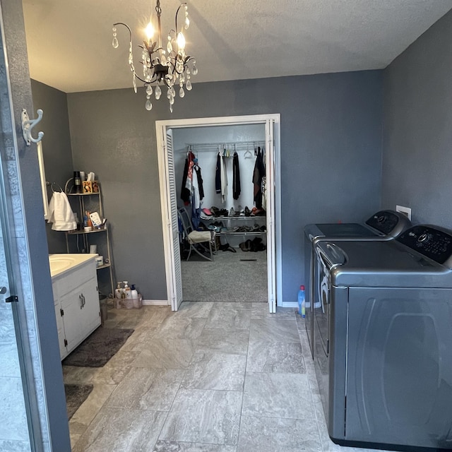 laundry room with washing machine and dryer, a chandelier, and a textured ceiling