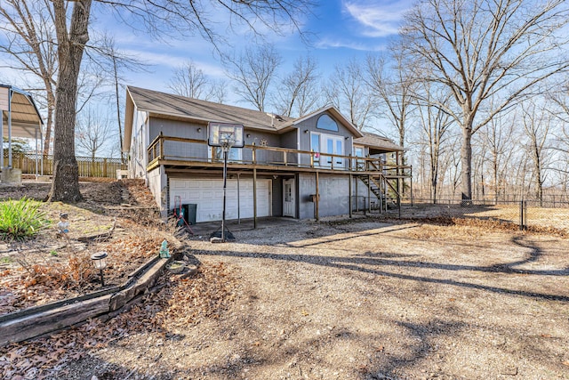 view of front of house featuring driveway, stairway, a wooden deck, and fence