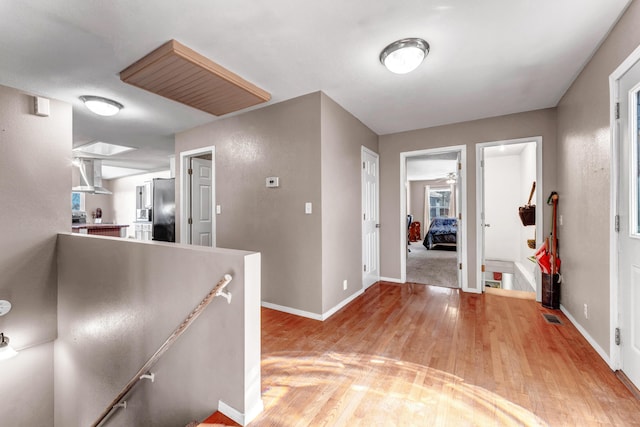 foyer entrance with light wood-type flooring, visible vents, and baseboards