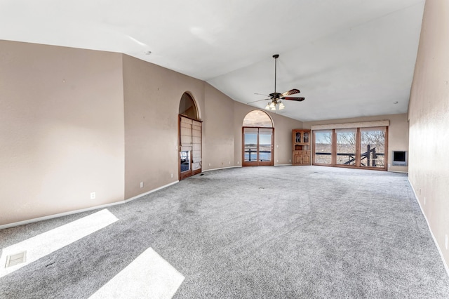 unfurnished living room with carpet, arched walkways, vaulted ceiling, ceiling fan, and baseboards