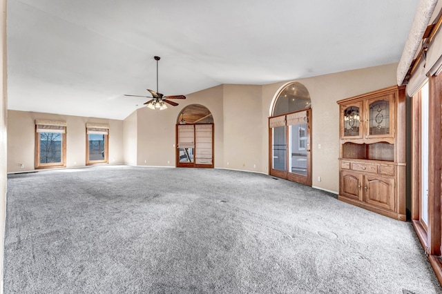 unfurnished living room featuring carpet floors, lofted ceiling, ceiling fan, and baseboards