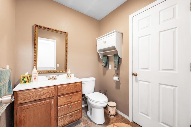 bathroom featuring toilet, baseboards, and vanity