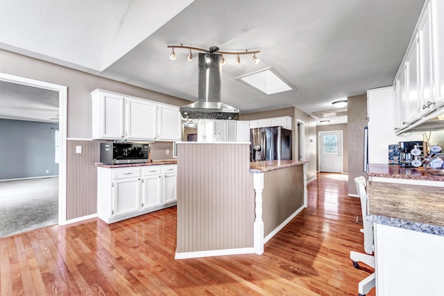 kitchen featuring appliances with stainless steel finishes, white cabinetry, light wood-style flooring, and range hood